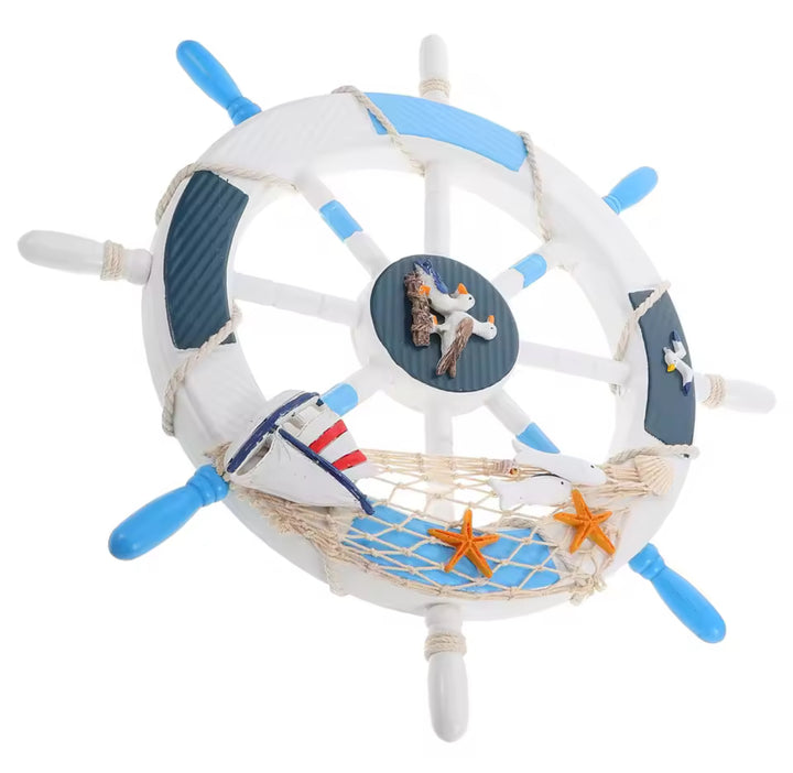 Blue and white decorative ship wheel wall hanging with sailboat, net, and seagull accents