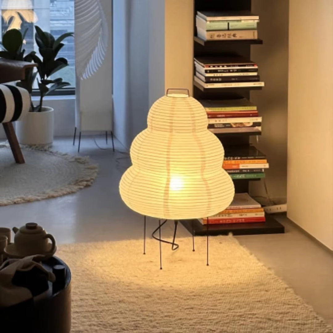 Sculptural warm white paper lantern floor lamp with a rounded layered shade and black metal legs in a modern living room