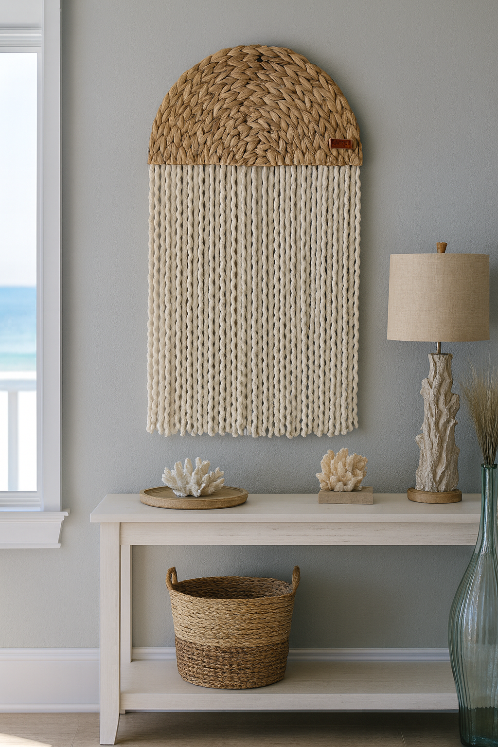 Handcrafted woven wall hanging with natural seagrass half-moon and cascading cotton tassels, coastal rustic décor.