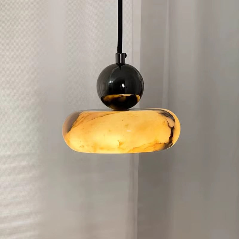 Modern amber alabaster pendant light with a black globe detail and sculptural stone shade