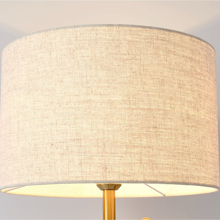 Modern brass floor lamp with cream linen drum shade and round stone base