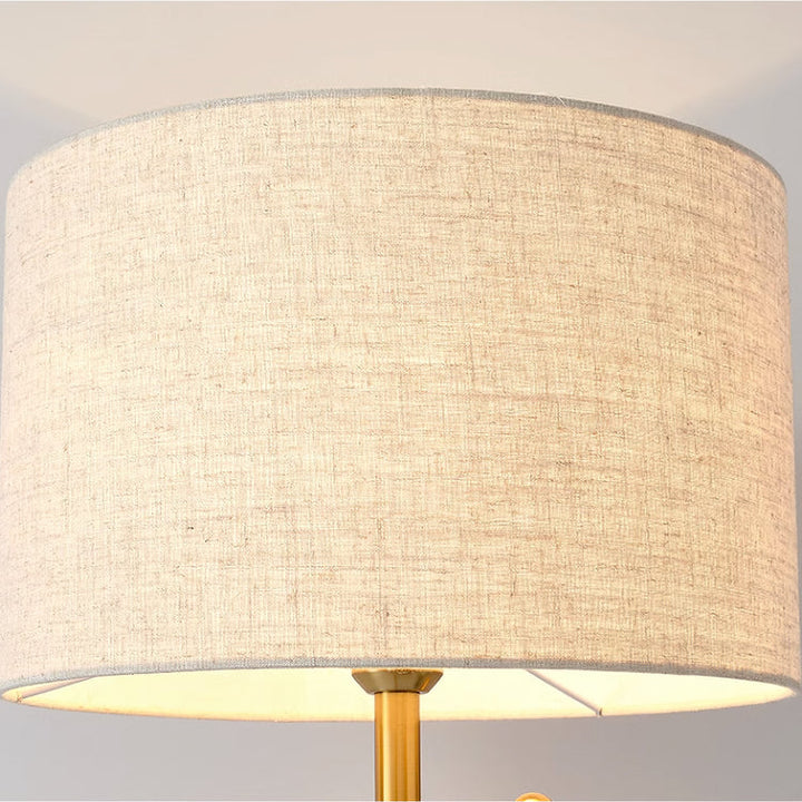 Modern brass floor lamp with cream linen drum shade and round stone base