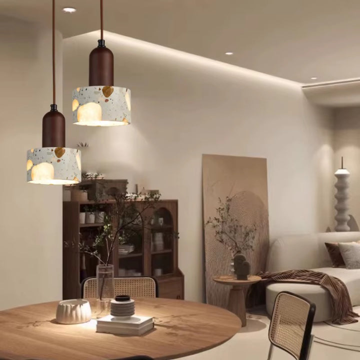 Close-up of a cream terrazzo pendant light shade with multicolored stone chips and a dark brown metal fitting