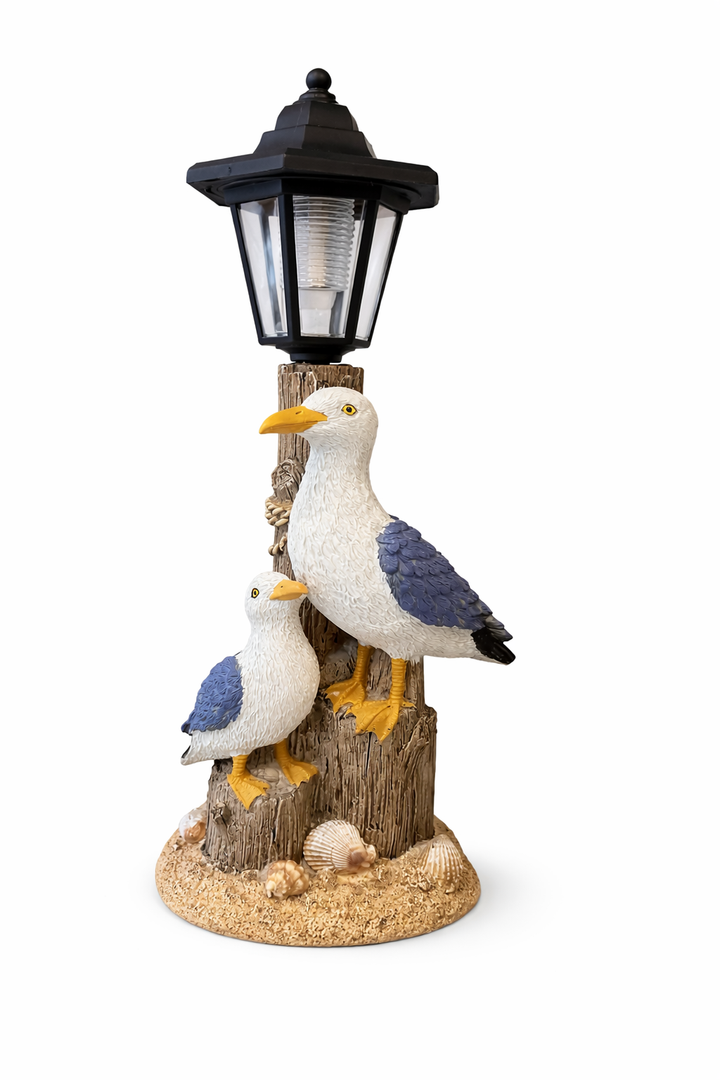Pelican lamp coastal sculpture with two seabirds on wooden posts and lantern-style light