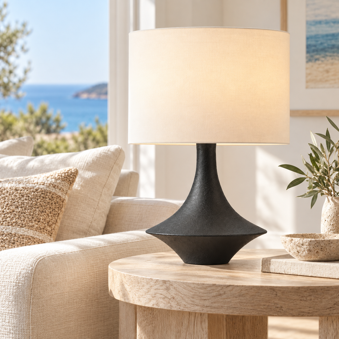 Modern black sculptural table lamp with cream fabric shade on a wooden side table