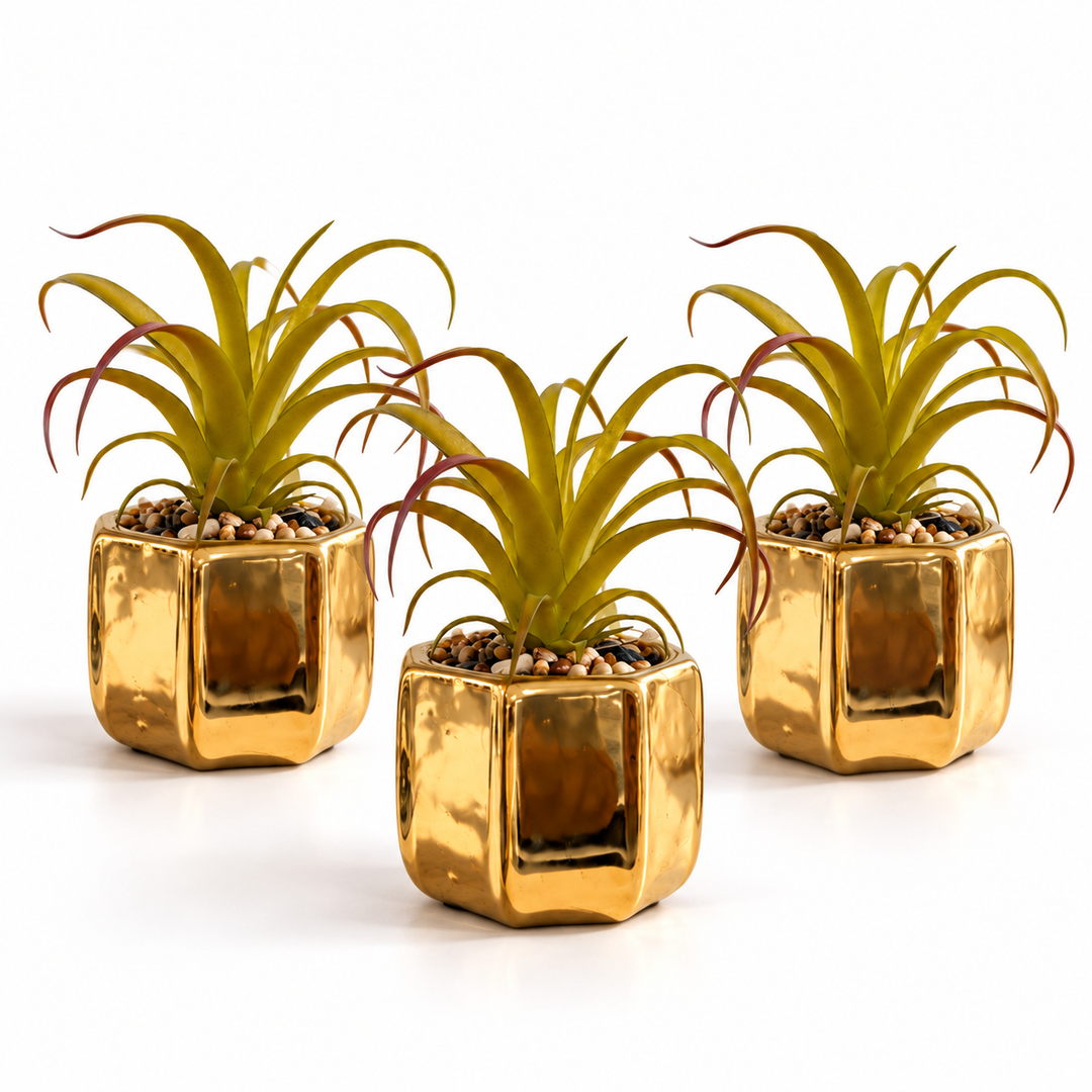 Set of three reflective gold ceramic planters with artificial ornamental green plants and decorative pebbles