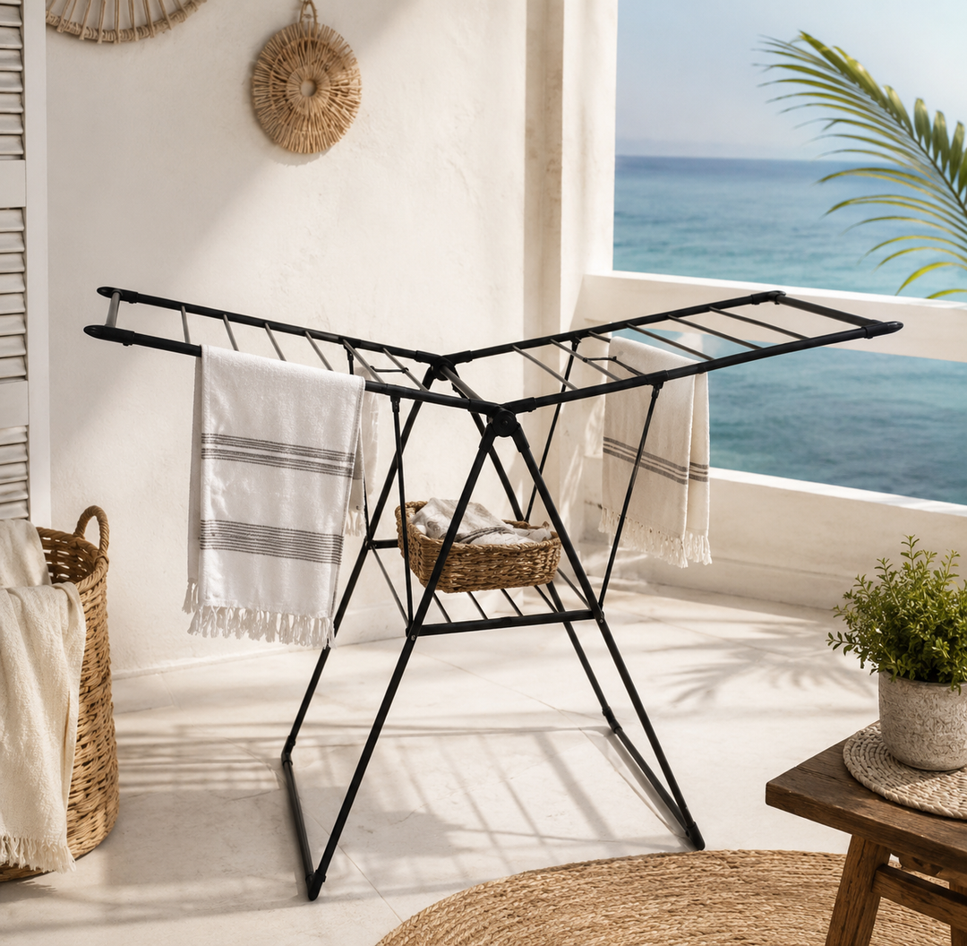 Foldable black metal clothes drying rack with multiple drying bars on a balcony.