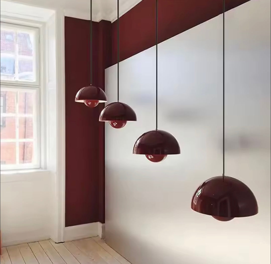 Cluster of glossy burgundy dome pendant lights suspended at different heights in a contemporary interior