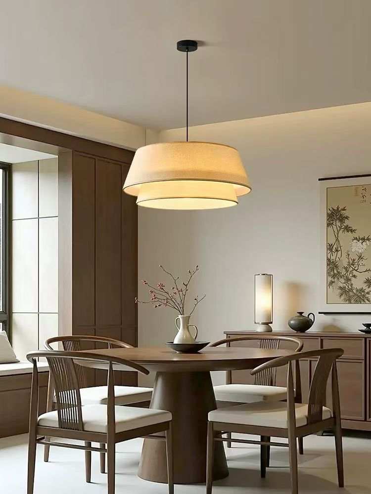 Layered fabric drum pendant with double-layer shade providing warm diffused dining light and soft modern elegance