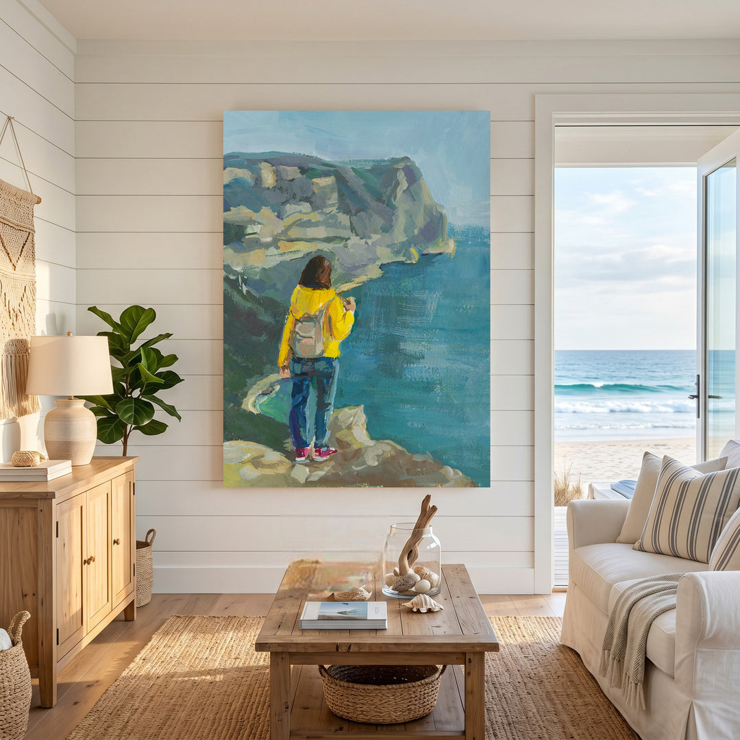 Wadi Home Coastal Cliffside Vista painting with a woman in yellow jacket overlooking the ocean.