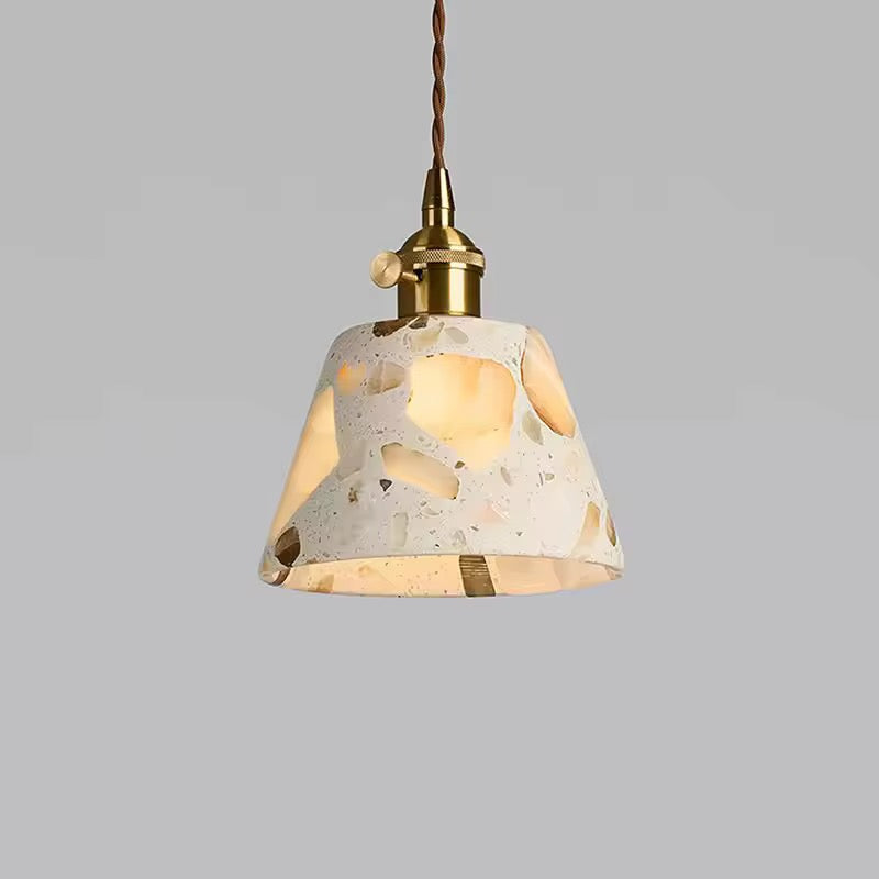 Cream terrazzo pendant light with an irregular shade, brass fitting, and twisted hanging cable