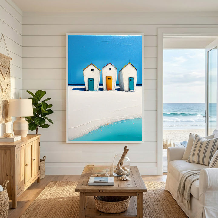 Wadi Home three white beach huts with blue and orange doors on a sunny beach with turquoise water.