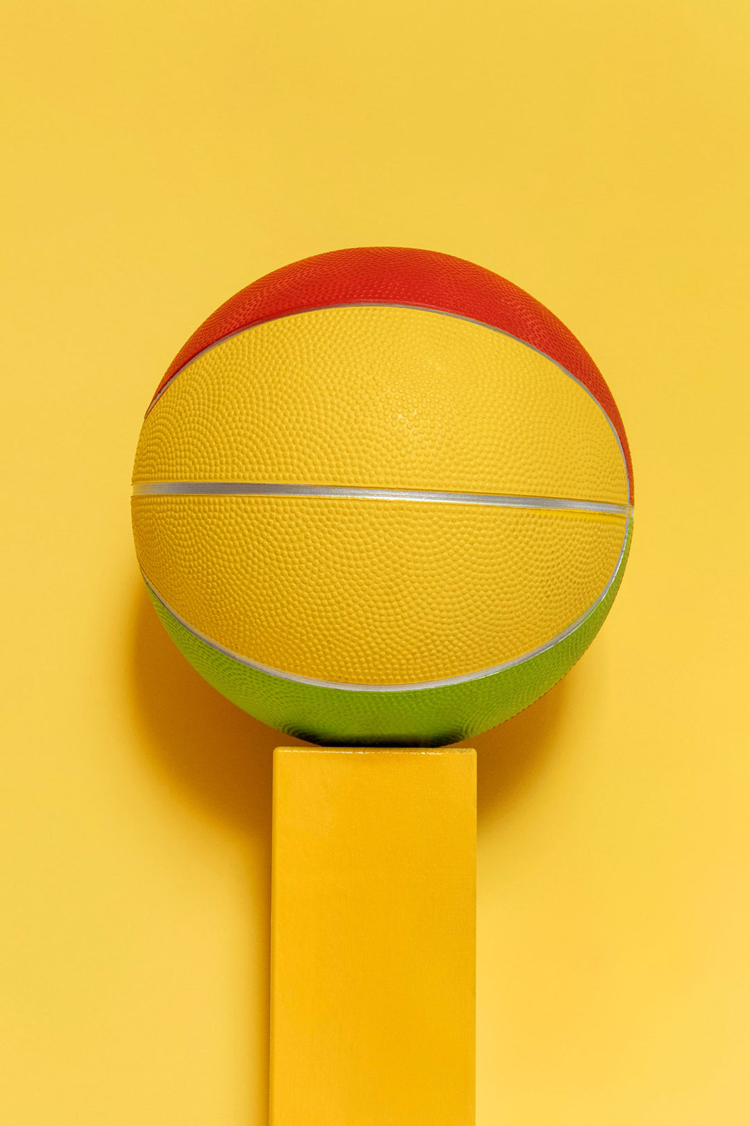 Wadi Home abstract geometric basketball art in yellow, red, and green, displayed on a yellow pedestal.