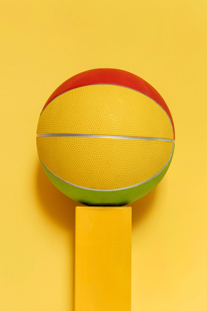Wadi Home abstract geometric basketball art in yellow, red, and green, displayed on a yellow pedestal.