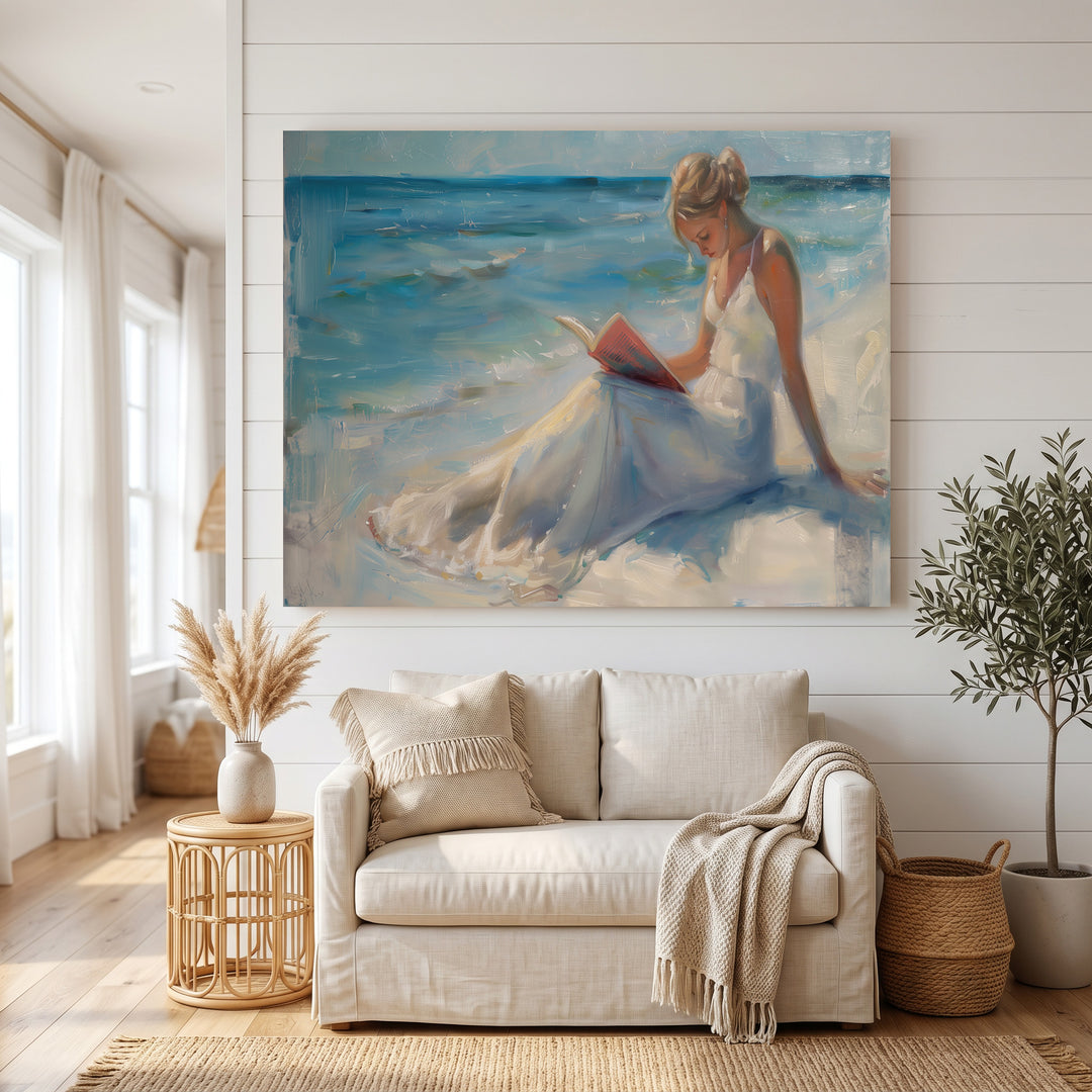 Wadi Home canvas art of a woman in a white dress reading a book on a serene beach with blue ocean waves.