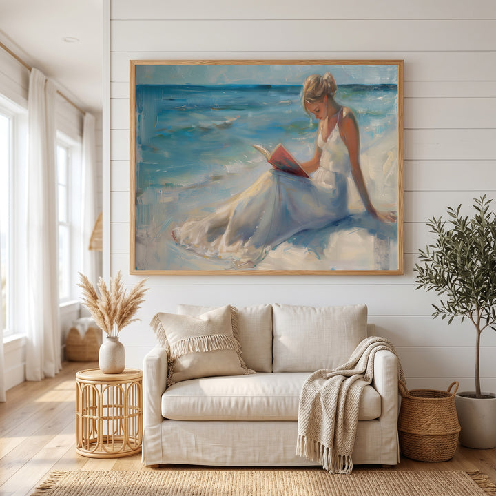 Wadi Home canvas wall art of a woman in a white dress reading a book on a serene beach with blue ocean waves.