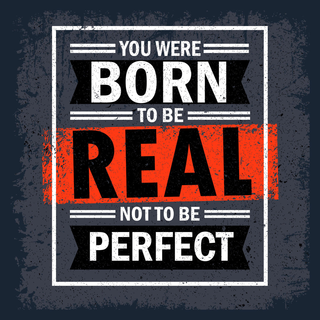 Wadi Home motivational wall art with bold white text on dark grey background: "You Were Born To Be Real Not To Be Perfect".