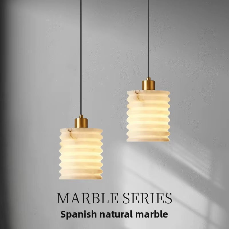 Pair of sculptural pendant lights made from Spanish natural marble with ribbed cylindrical shades and warm illumination