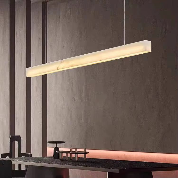 Modern linear ivory pendant light suspended above a dining table in a contemporary interior