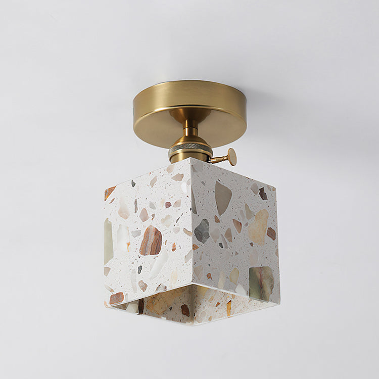 White terrazzo cube pendant light with multicolor stone chips and a brass ceiling mount