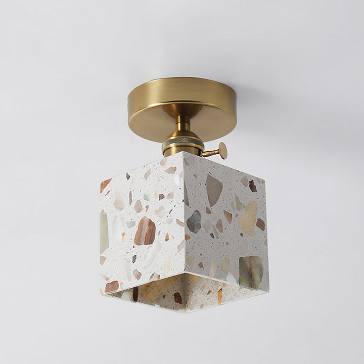 White terrazzo cube pendant light with multicolor stone chips and a brass ceiling mount