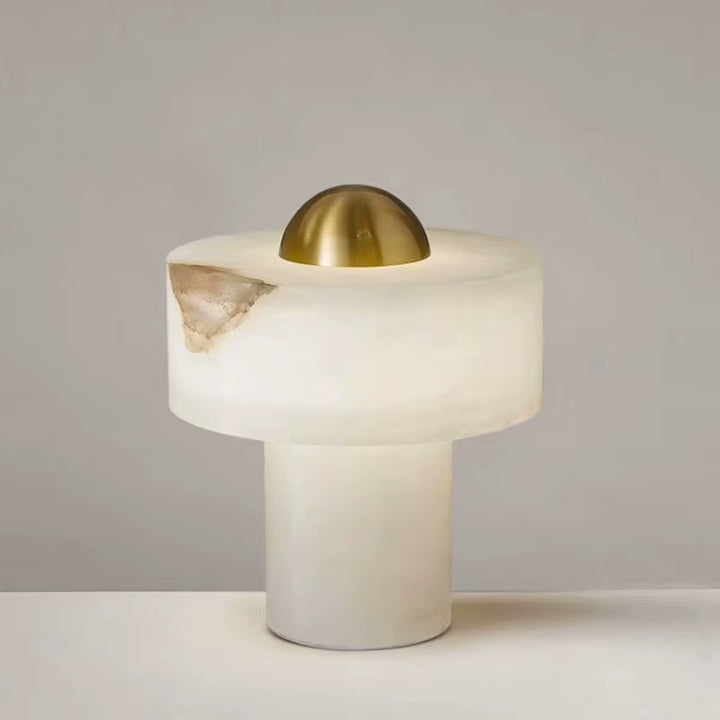 Modern white table lamp with a cylindrical base, rounded diffuser, and brass dome accent