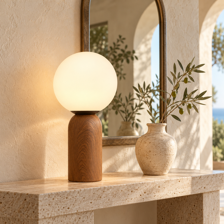 Table lamp with a brown cylindrical base and glowing white globe shade on a stone console
