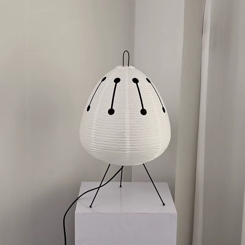 White pleated tripod table lamp with black decorative accents and a rounded shade