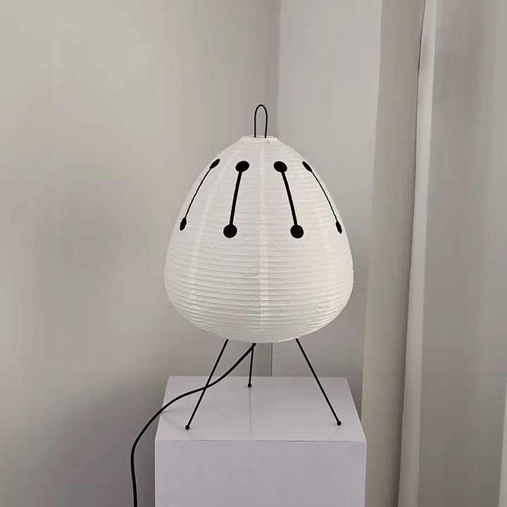 White pleated tripod table lamp with black decorative accents and a rounded shade