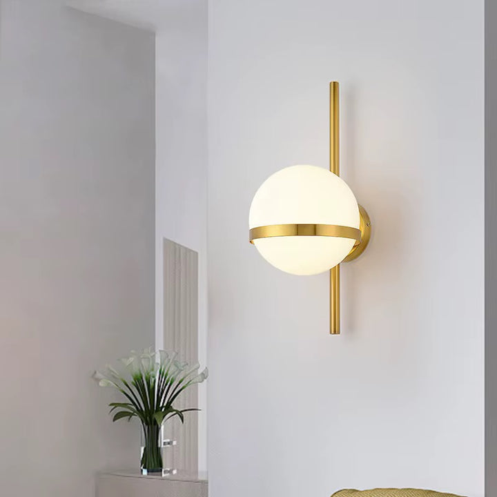 Modern gold globe wall sconce with a frosted spherical shade mounted on a white wall