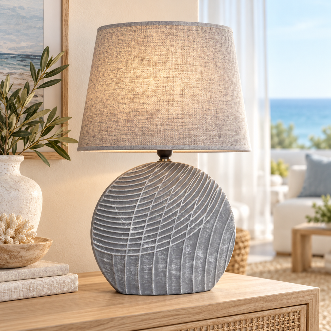 Sculptural gray table lamp with a textured rounded base and beige fabric shade on a wooden console