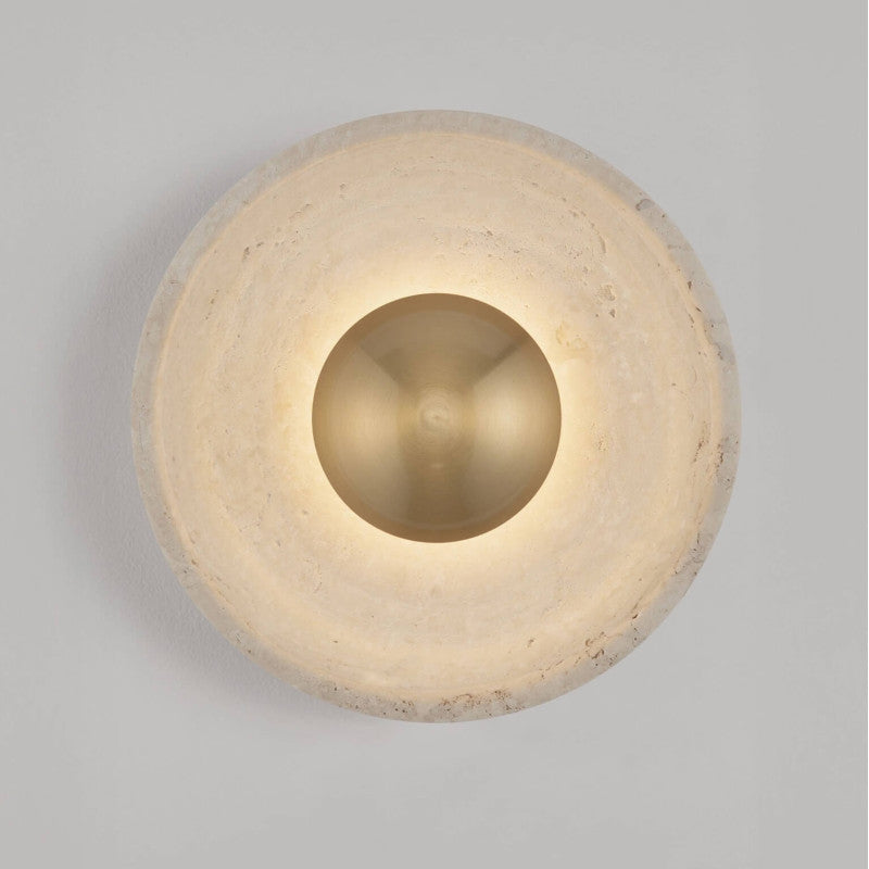 Round wall sconce with a softly glowing recessed center and textured pale cream circular surround, mounted on a light gray wall.