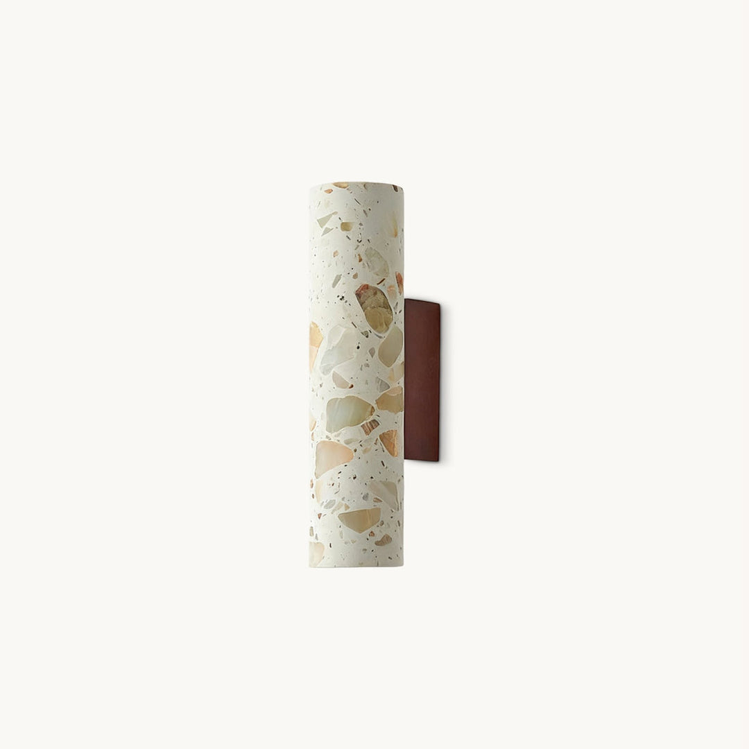 Slim cylindrical cream terrazzo wall sconce with multicolored stone flecks and a brown wall mount
