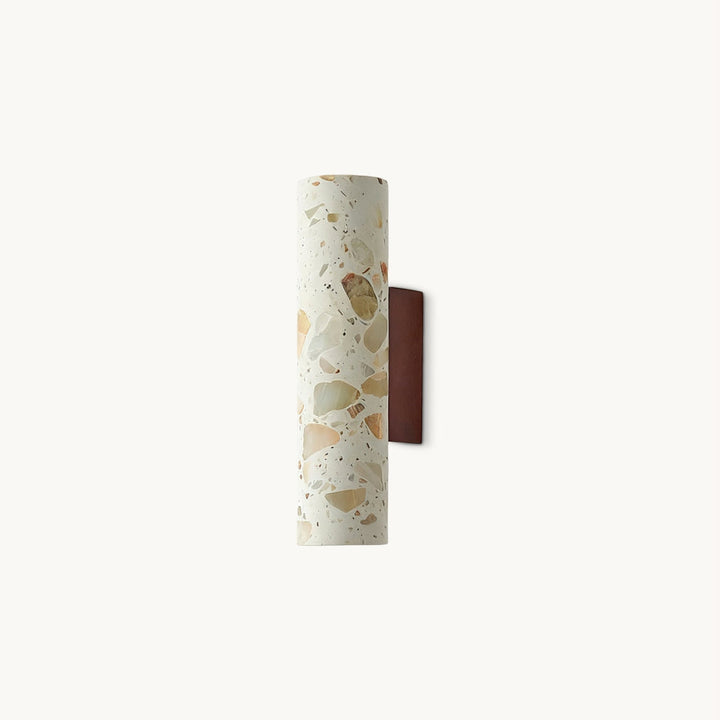 Slim cylindrical cream terrazzo wall sconce with multicolored stone flecks and a brown wall mount
