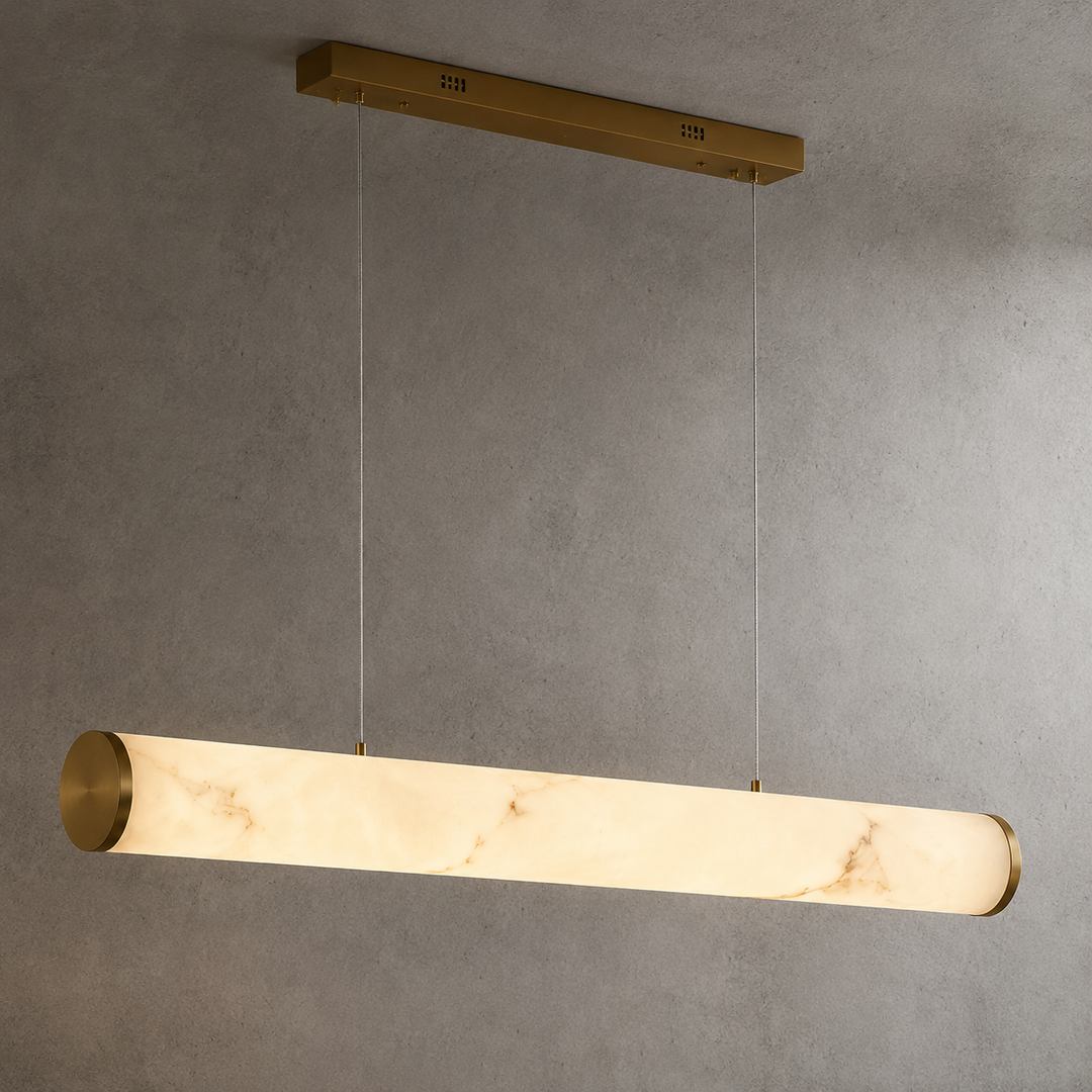 Modern linear marble-effect LED pendant light with brass end caps and dual cable suspension.
