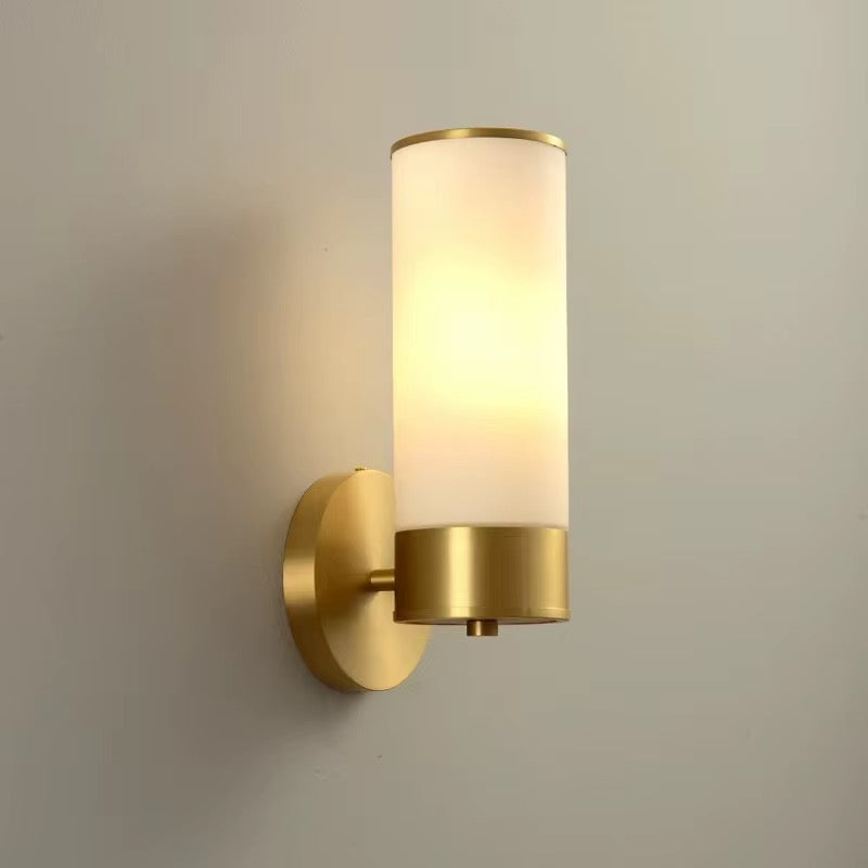 Modern brass wall sconce with a tall cylindrical opal glass shade