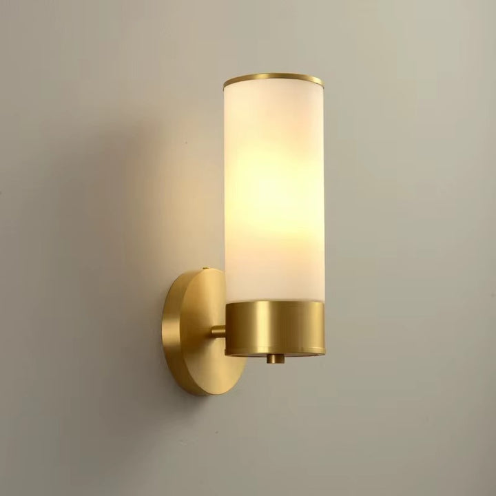 Modern brass wall sconce with a tall cylindrical opal glass shade