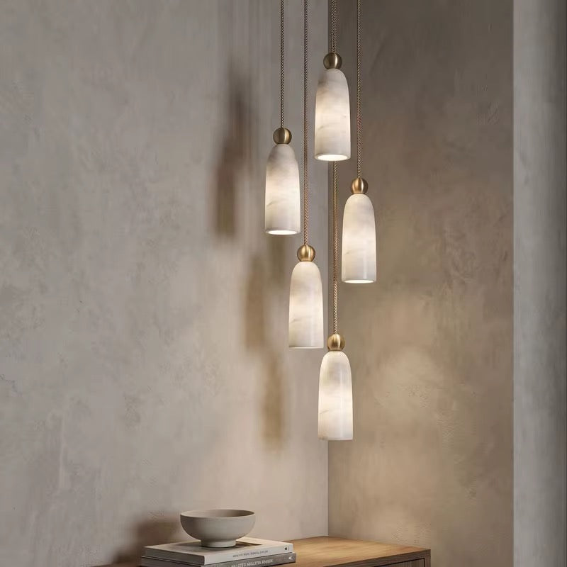 Five cream veined pendant lights at staggered heights with gold-tone fittings