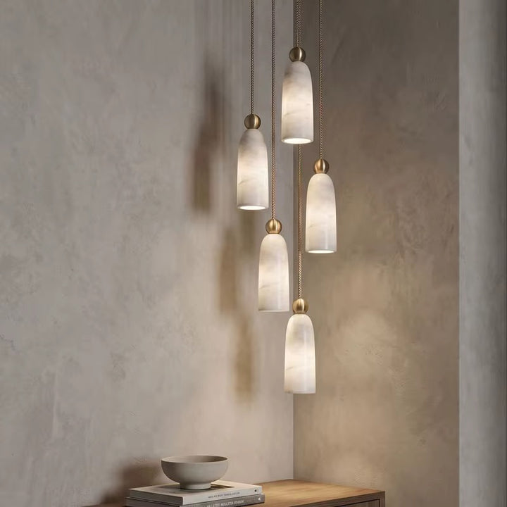 Five cream veined pendant lights at staggered heights with gold-tone fittings