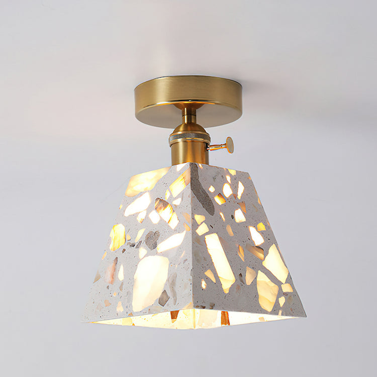 White terrazzo cone pendant light with translucent openings and a brass-colored ceiling fitting