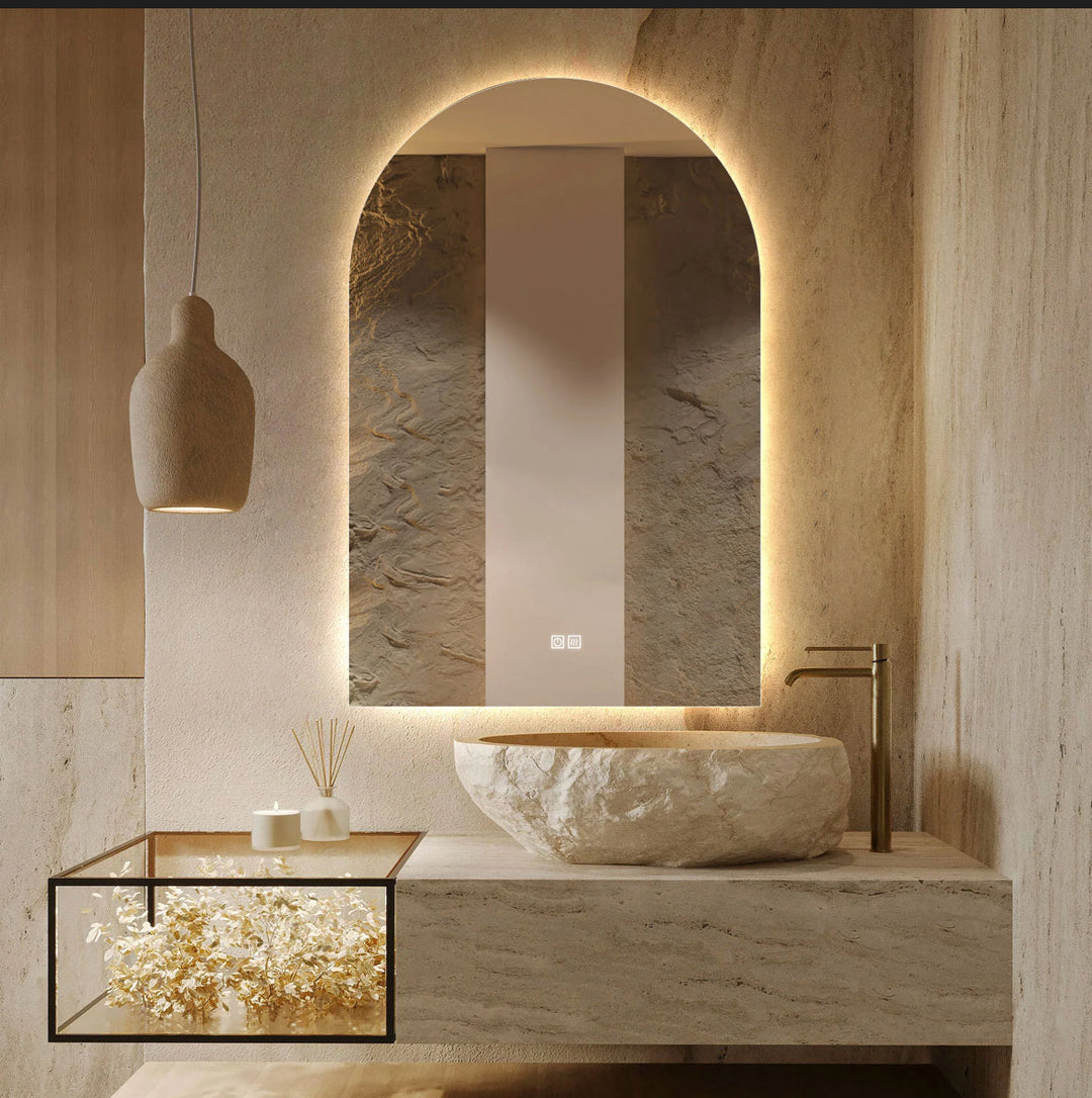 Modern bathroom with stone sink, illuminated mirror, and decorative elements.