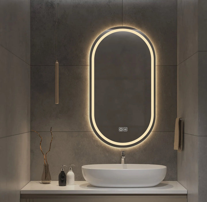 Bathroom vanity with a illuminated oval mirror and sink.