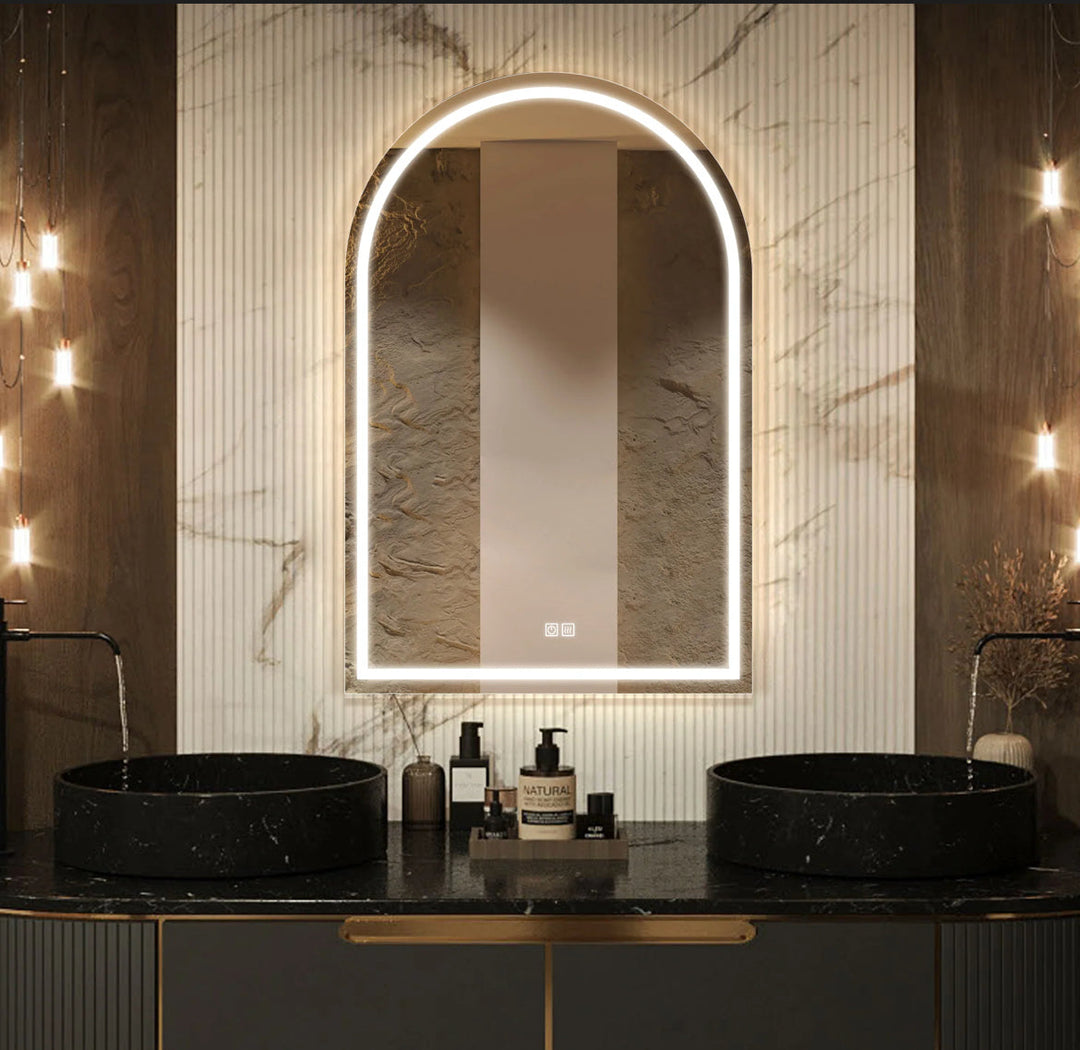 Bathroom vanity with a large illuminated mirror, black sinks, and decorative lighting.