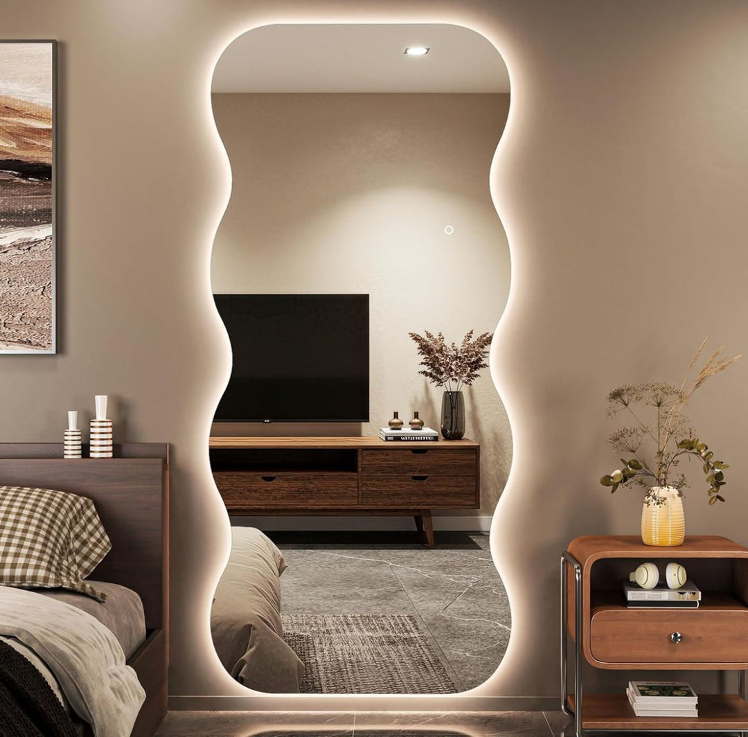 Modern bedroom with a large illuminated mirror reflecting a television and decor.