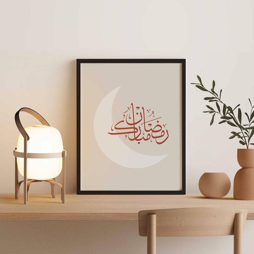 Framed artwork with Arabic calligraphy on a wall above a wooden shelf with a lamp and plant.