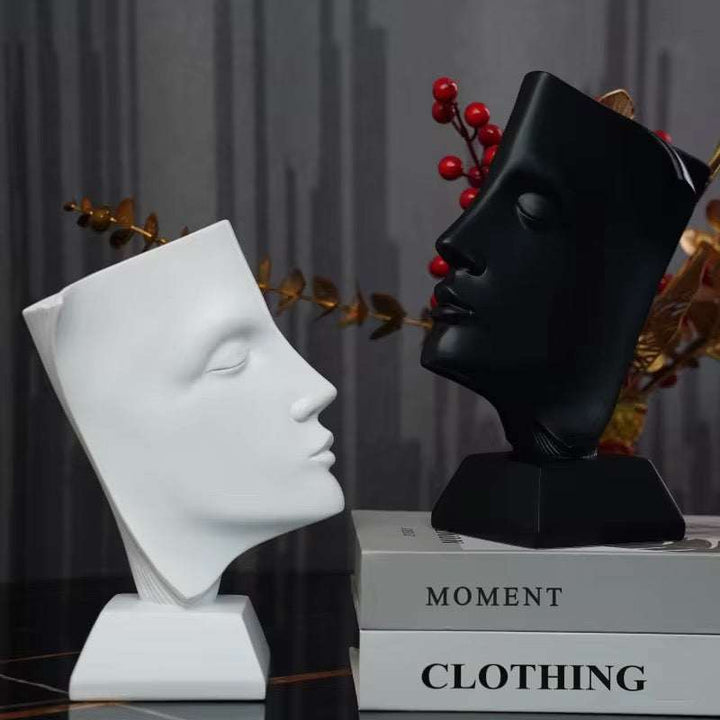 Modern abstract face sculpture with minimalist black and white design on a shelf