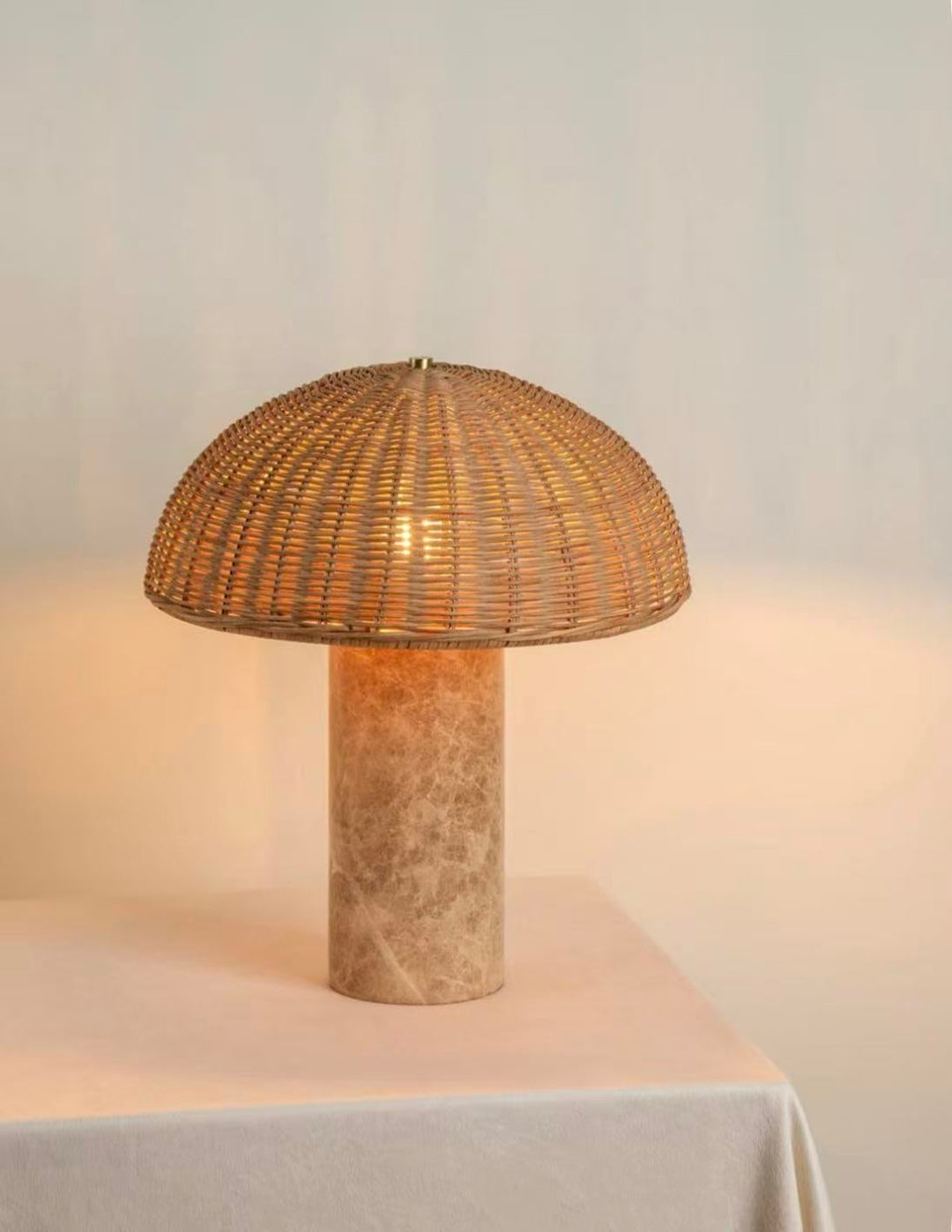 Rattan dome table lamp with woven shade and marble base emitting warm light