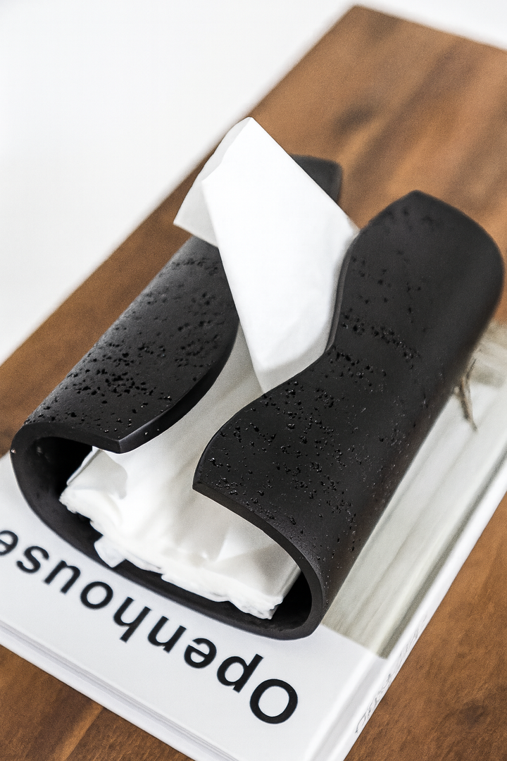 Modern curved black tissue holder with matte textured finish and minimalist design