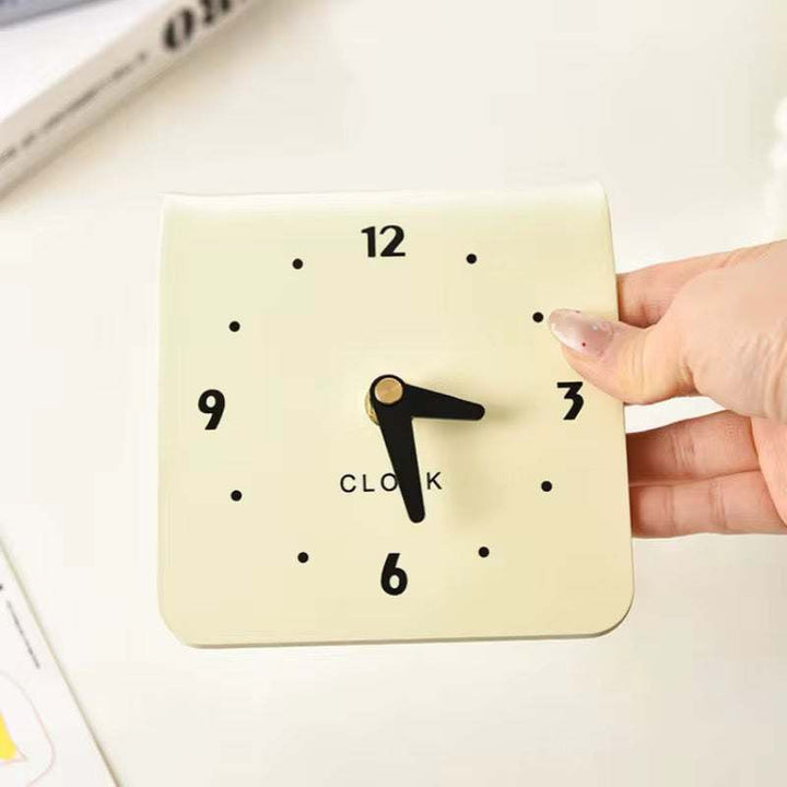 Modern folded desk clock with cream finish and bold numeric design on curved silhouette
