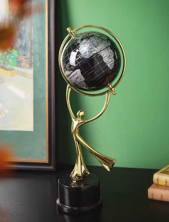 Golden globe holder sculpture with black globe on modern décor display